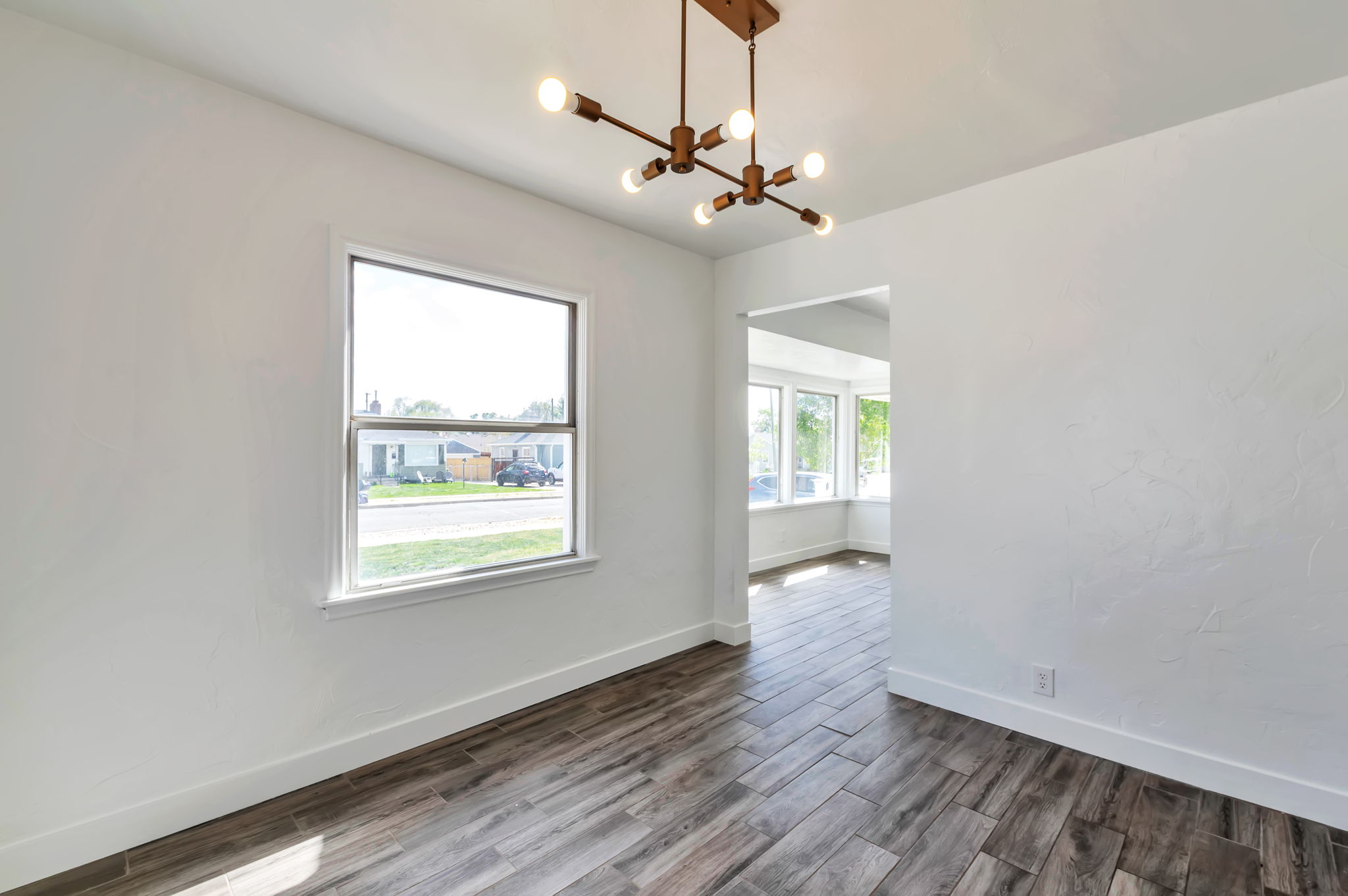 Unfurnished room featuring dark wood-style flooring and hanging lights