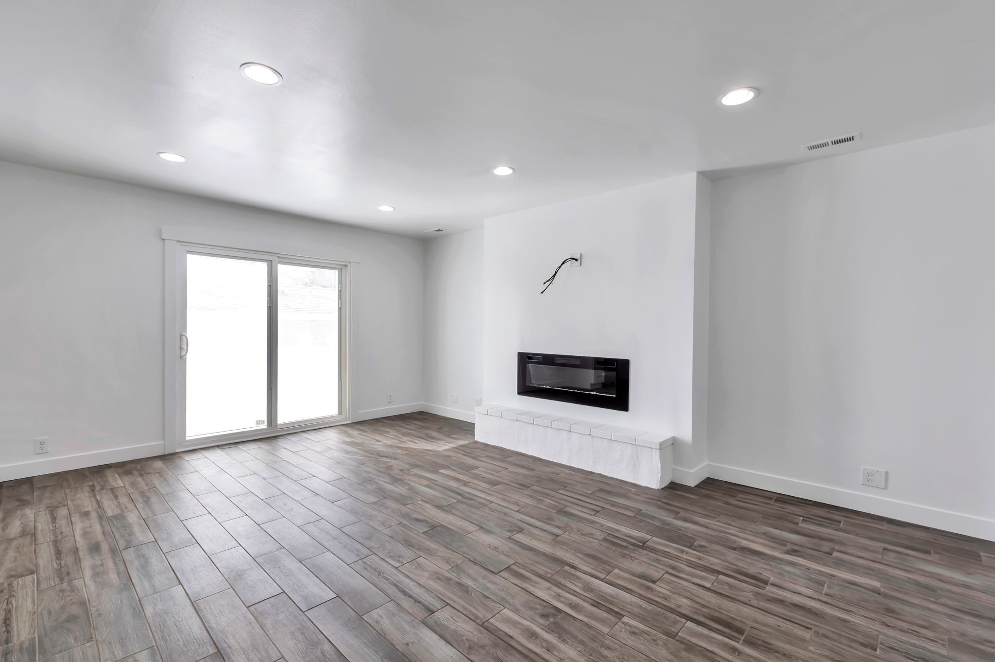 Unfurnished living room with wood tiled floors, a glass covered fireplace, and recessed lighting