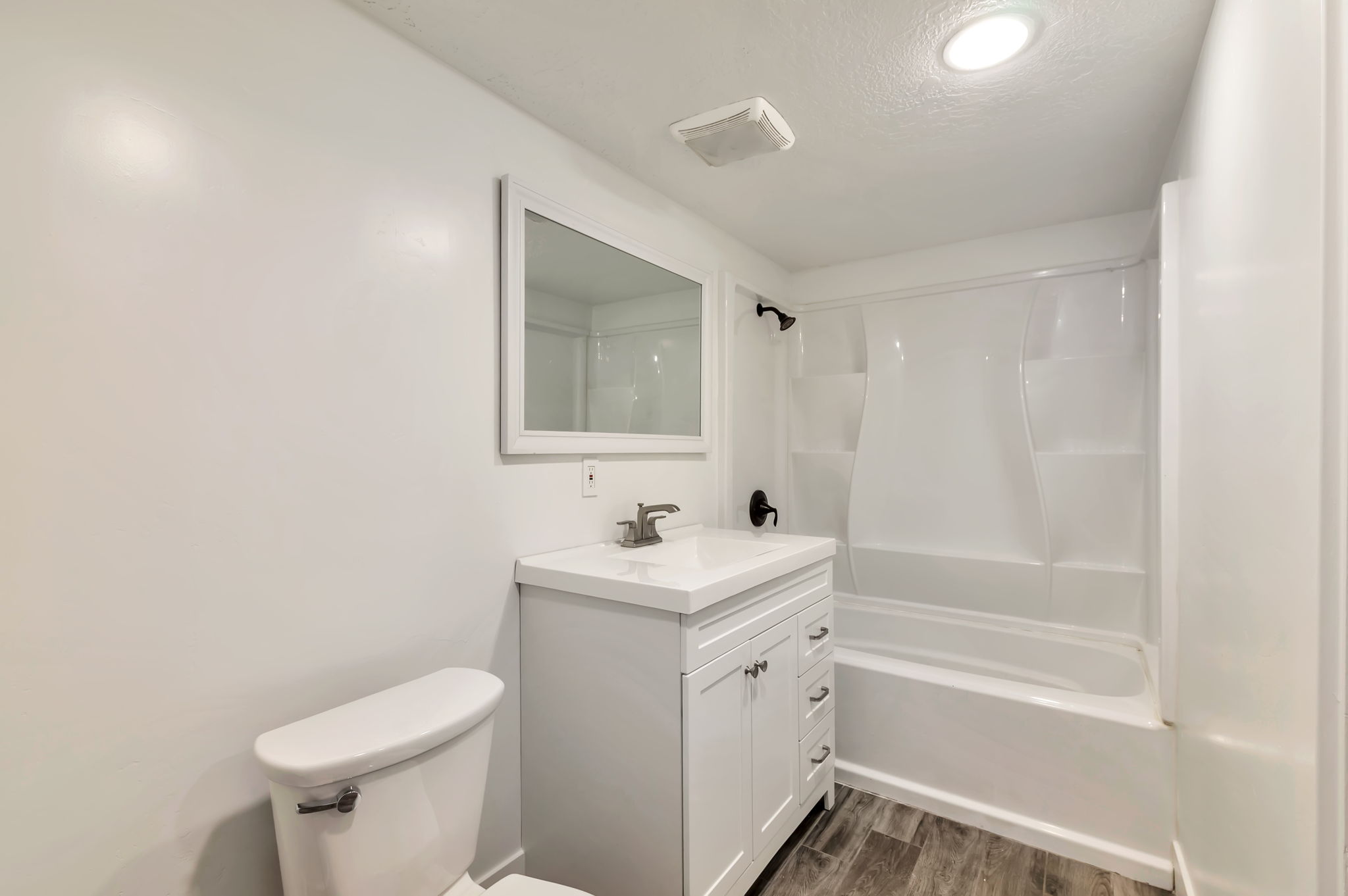 Full bathroom featuring vanity, dark wood-style floors, shower / bath combination, and a textured ceiling
