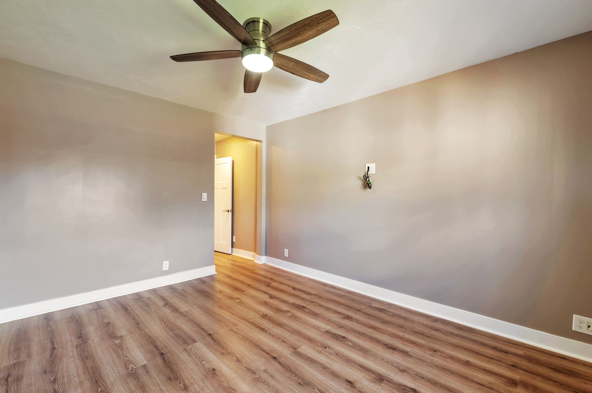 Empty room with light wood finished floors and a ceiling fan