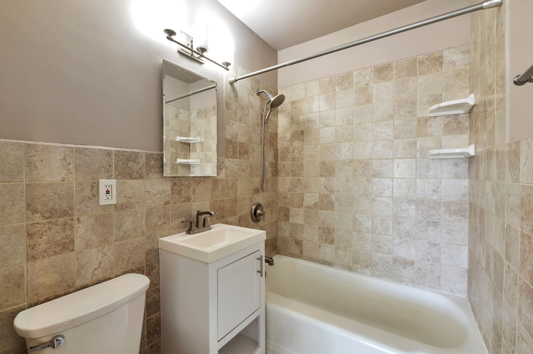 Full bathroom featuring vanity, shower / washtub combination, and tile walls