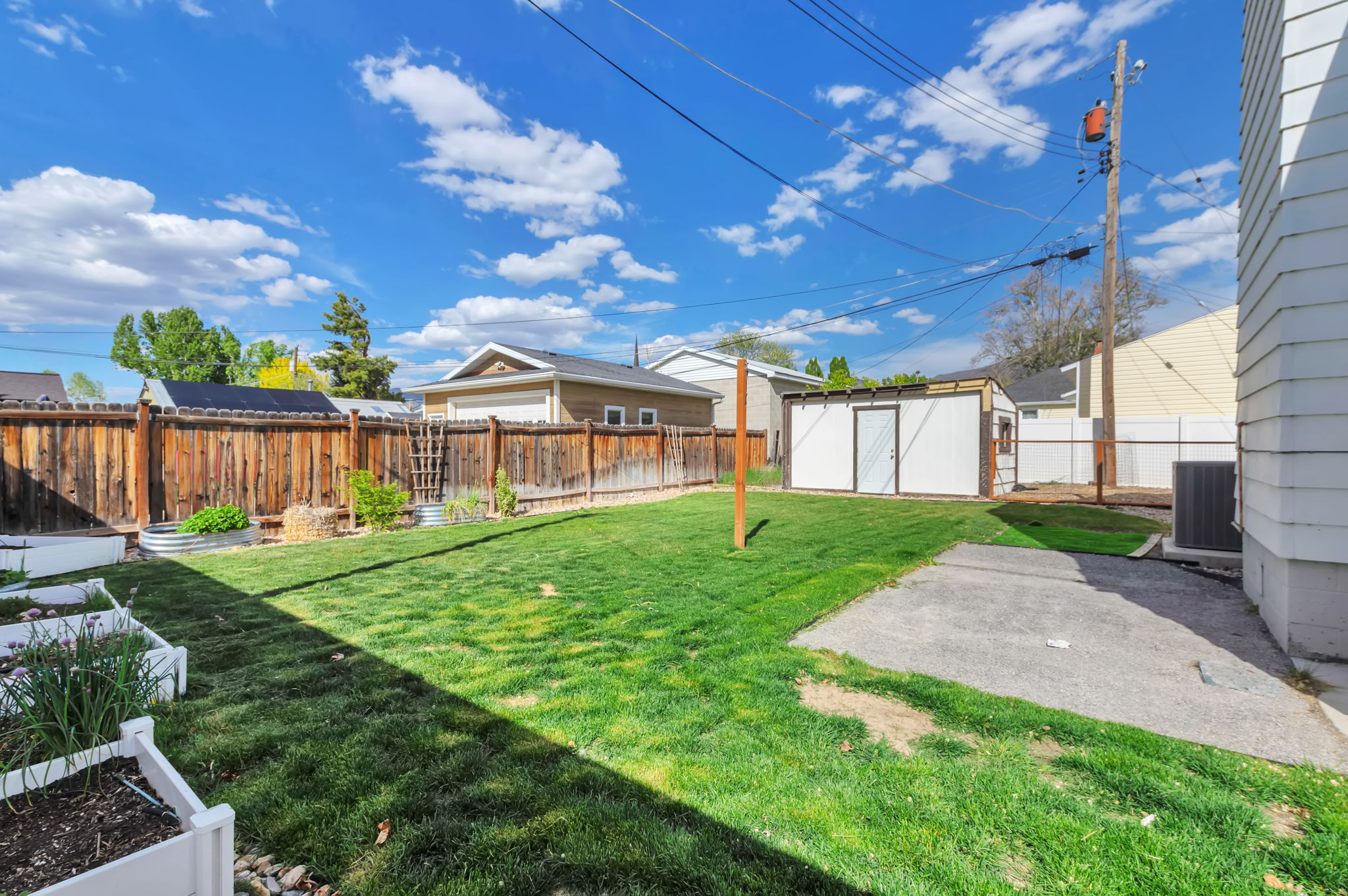 Fenced backyard with a storage shed, a vegetable garden, and a patio area