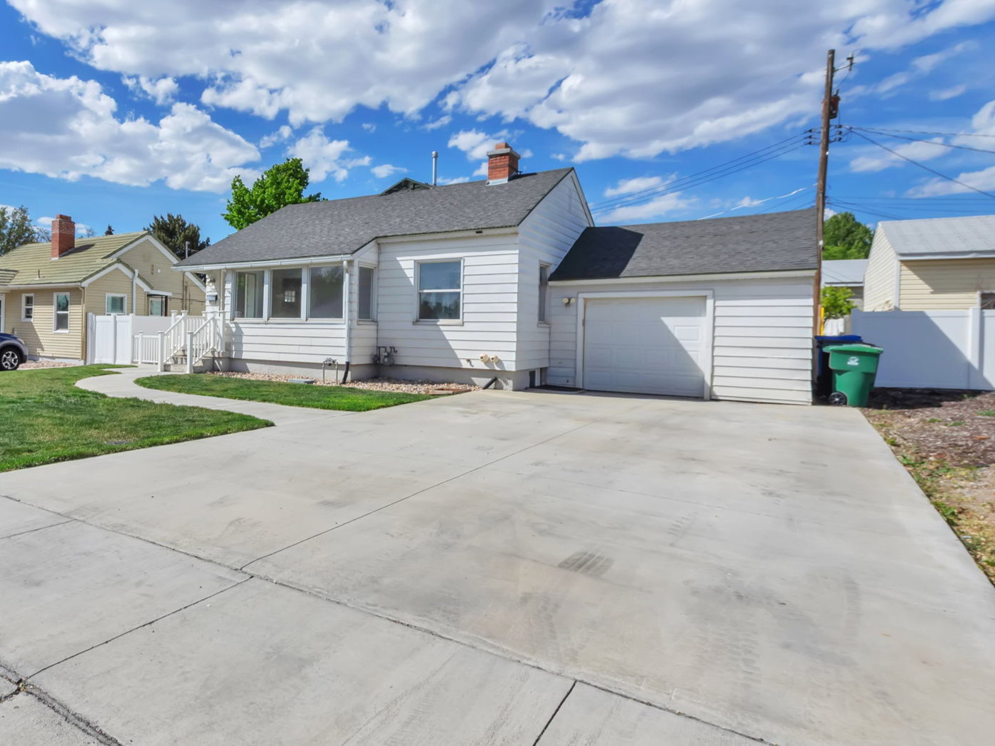 View of front of house with concrete driveway, a garage, a chimney, a residential view, and a shingled roof