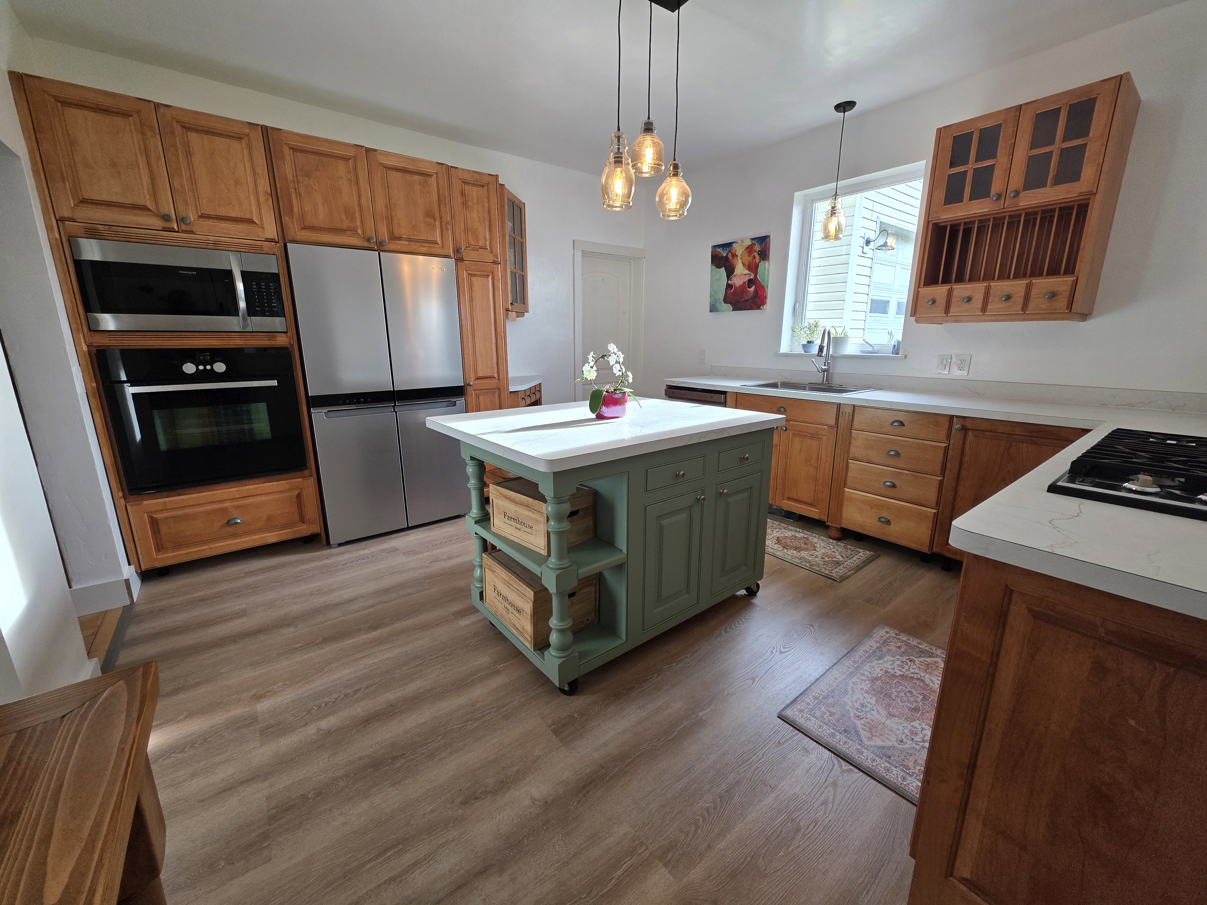 Kitchen featuring black appliances, light countertops, a kitchen island, dark wood-style flooring, and two tone cabinetry
