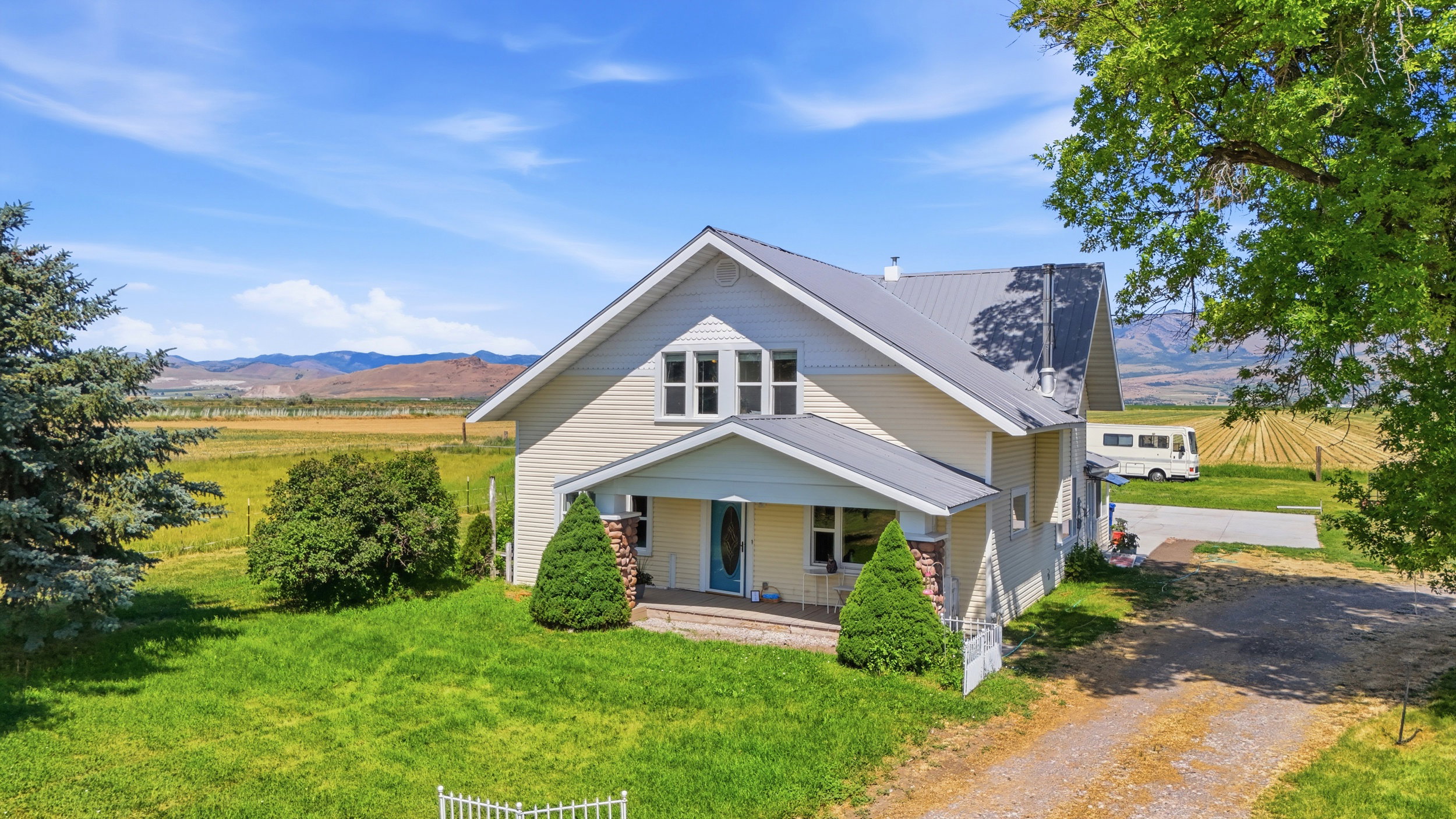 Expansive property featuring a two-story residence with light-colored siding and a metal roof