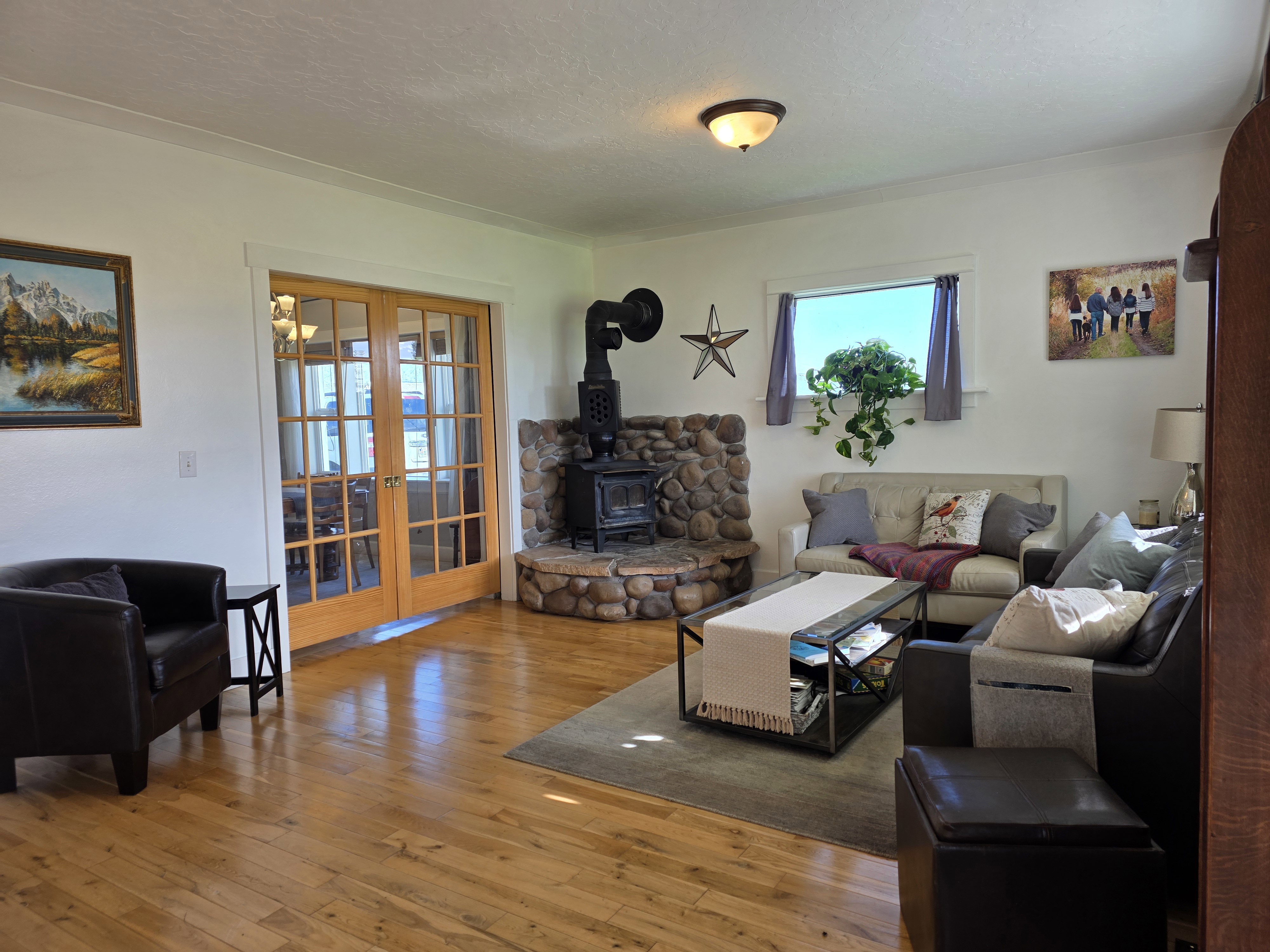Living room with french doors, hardwood / wood-style floors, and a wood stove
