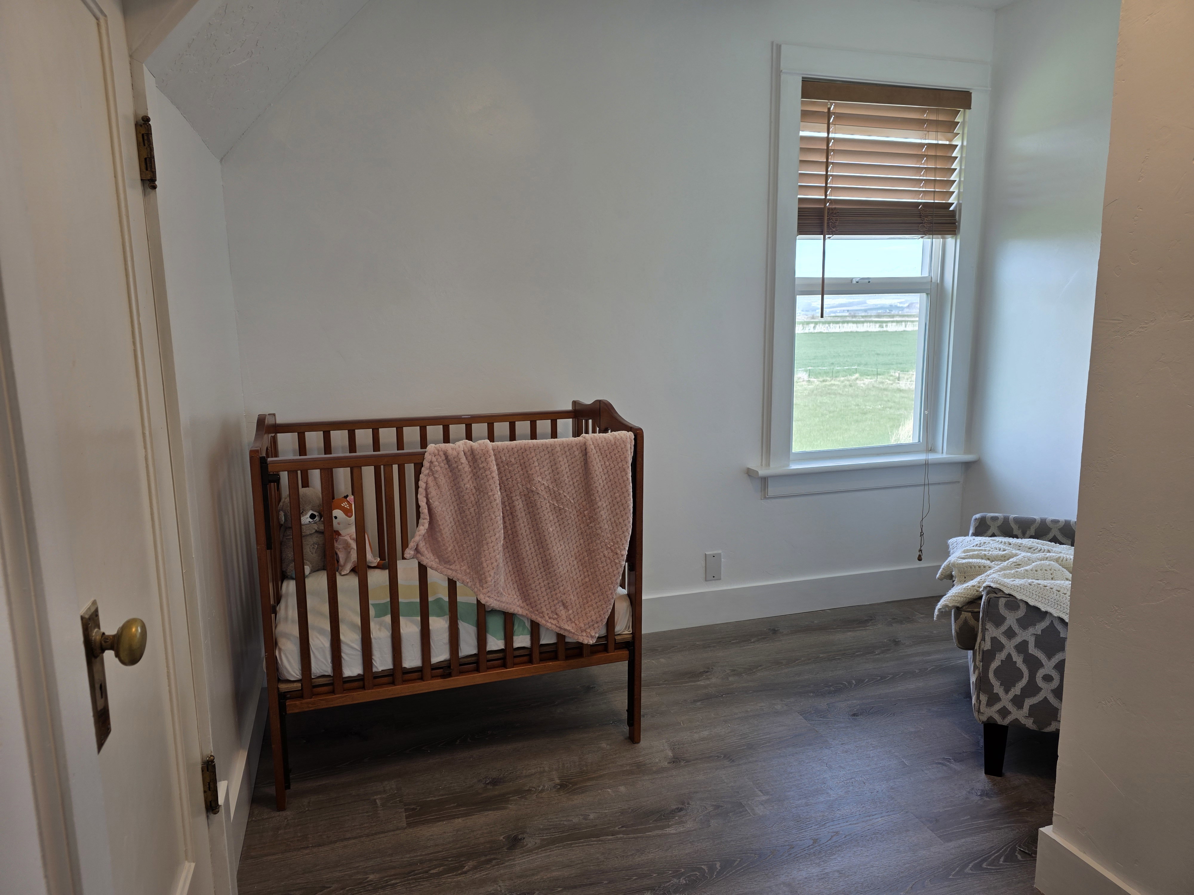 Bedroom with a crib, dark wood-style flooring, and lofted ceiling
