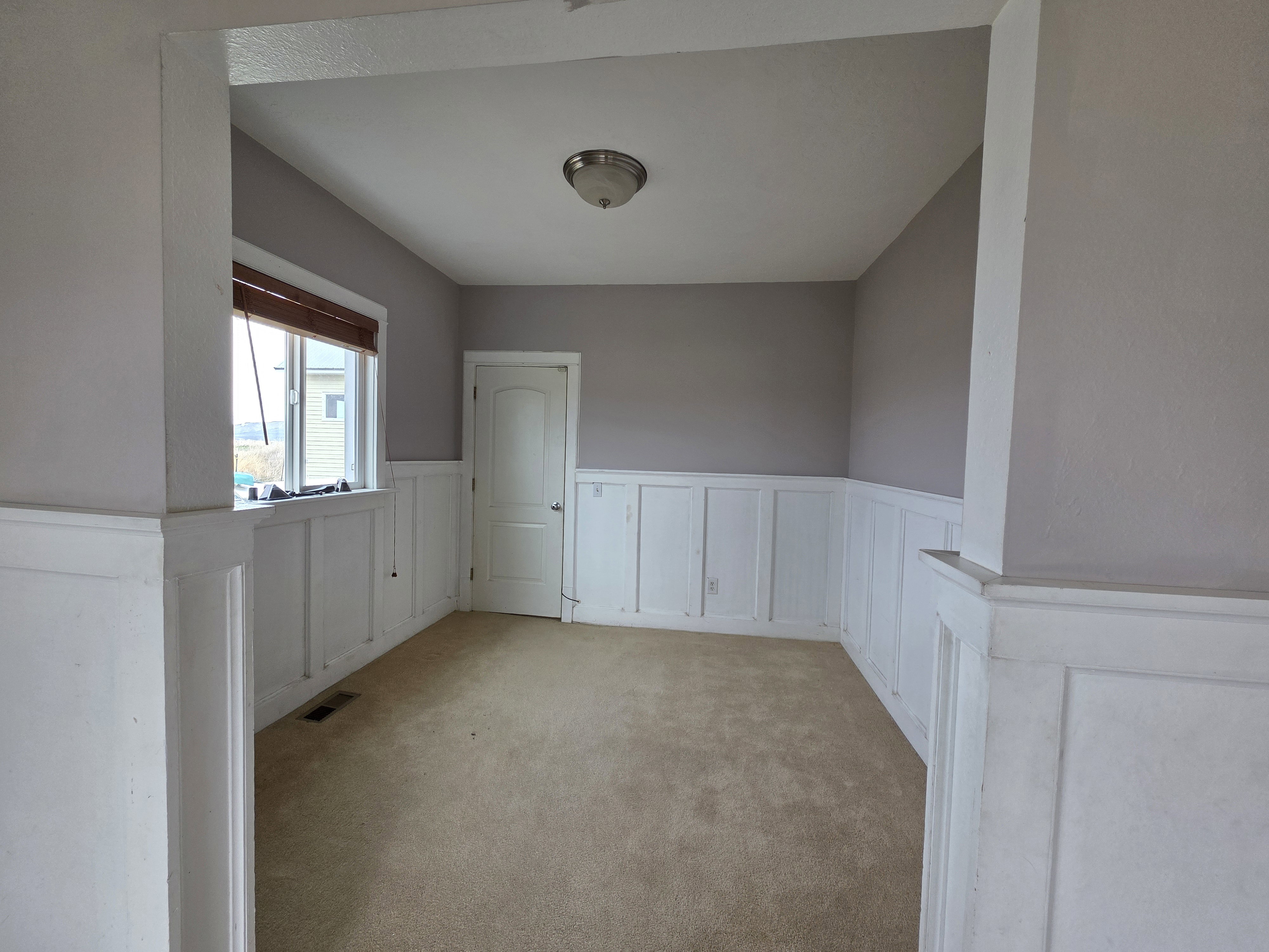 Spare room featuring a wainscoted wall, a decorative wall, and carpet flooring