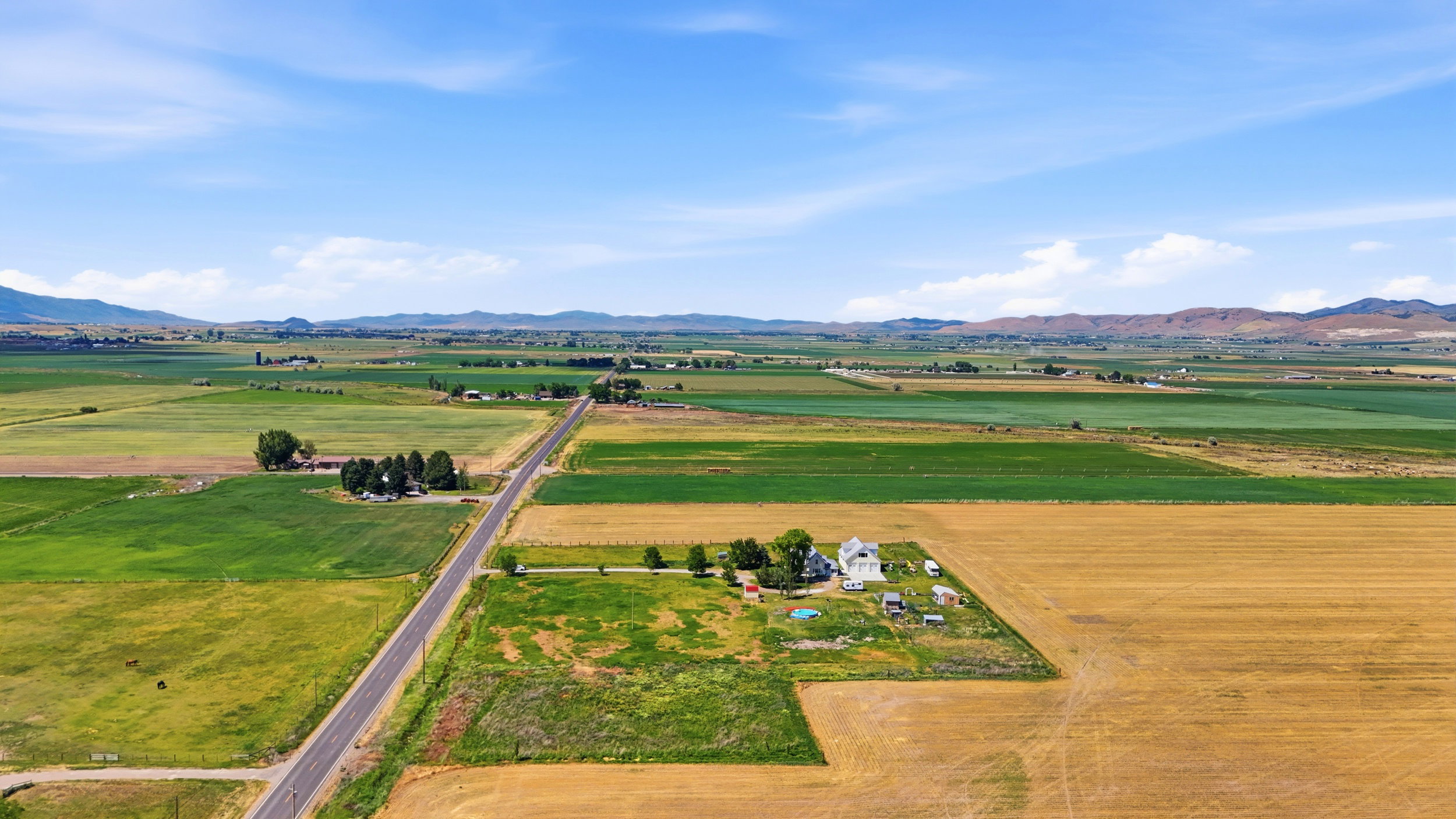 Expansive aerial landscape featuring agricultural fields and distant mountainous terrain