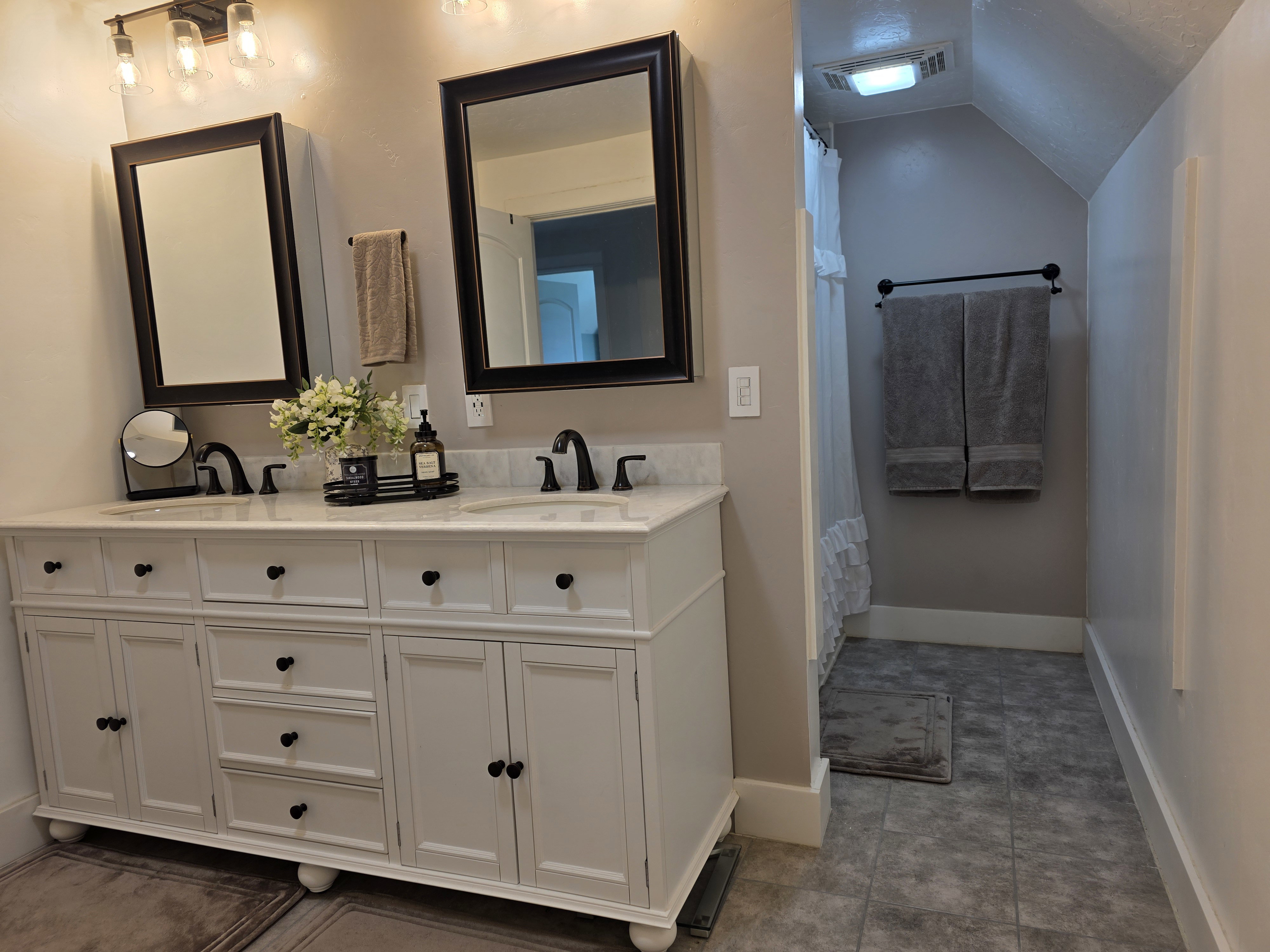 Full bathroom featuring double vanity, vaulted ceiling, and a shower with shower curtain