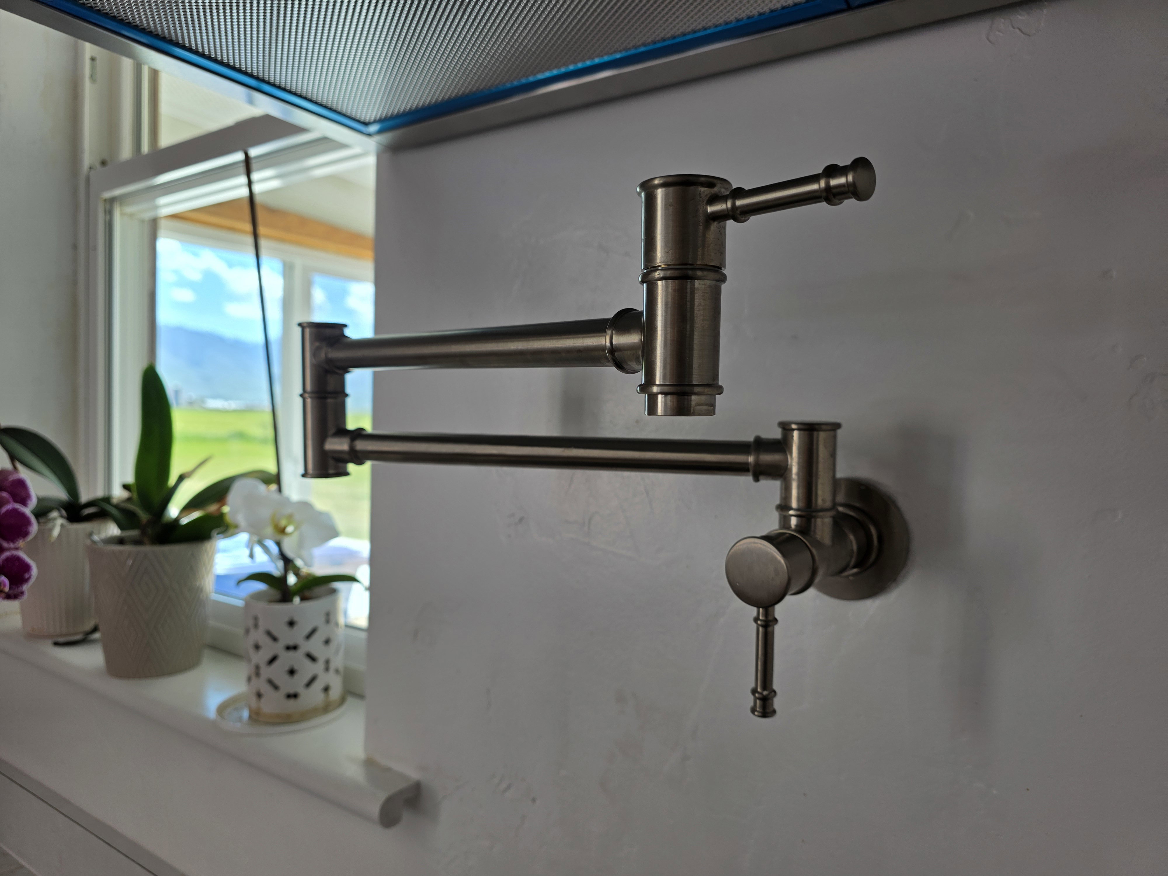 Wall-mounted pot filler with a brushed metal finish