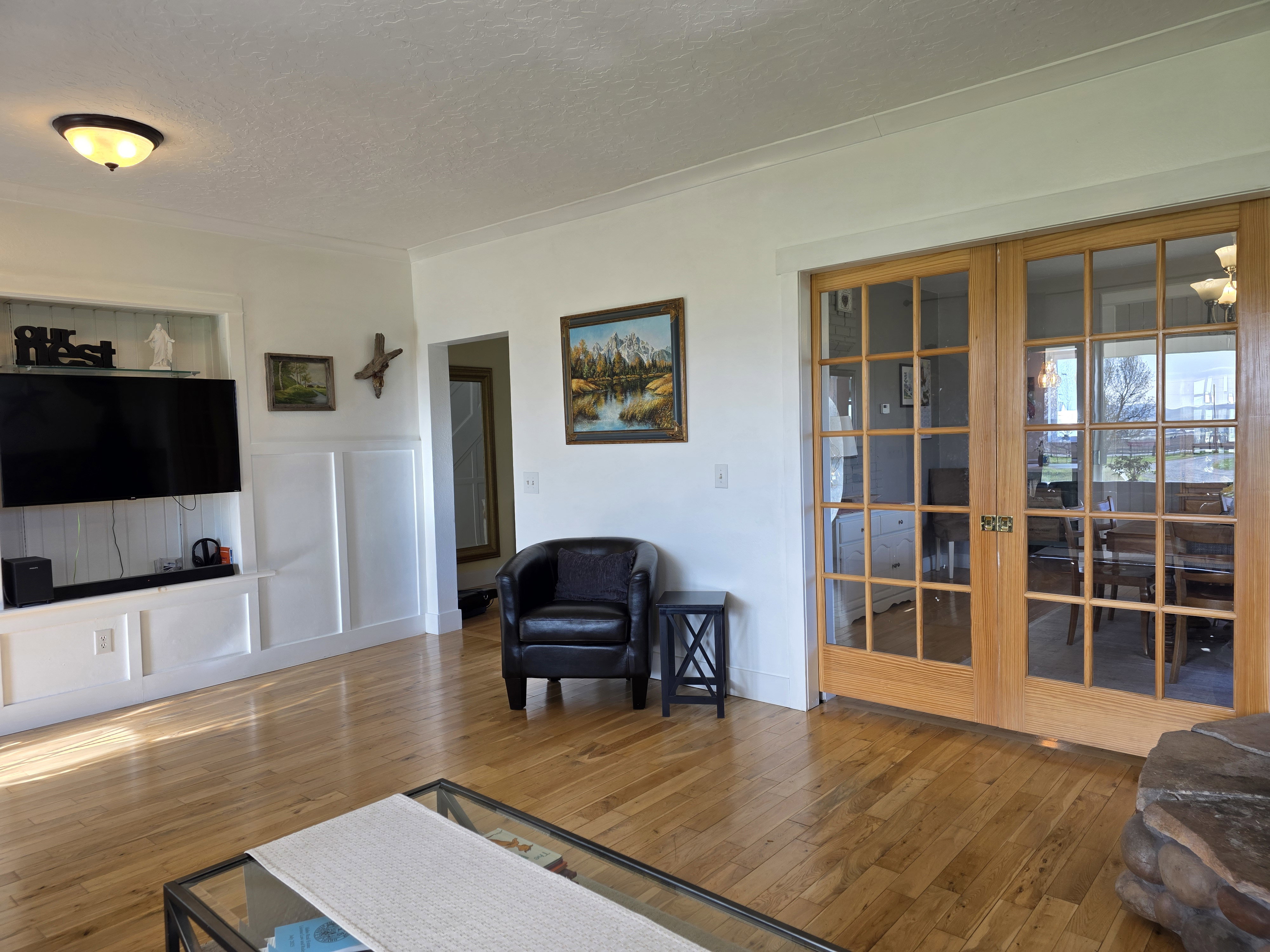 Living room featuring hardwood / wood-style flooring, a textured ceiling, french doors, and a decorative wall