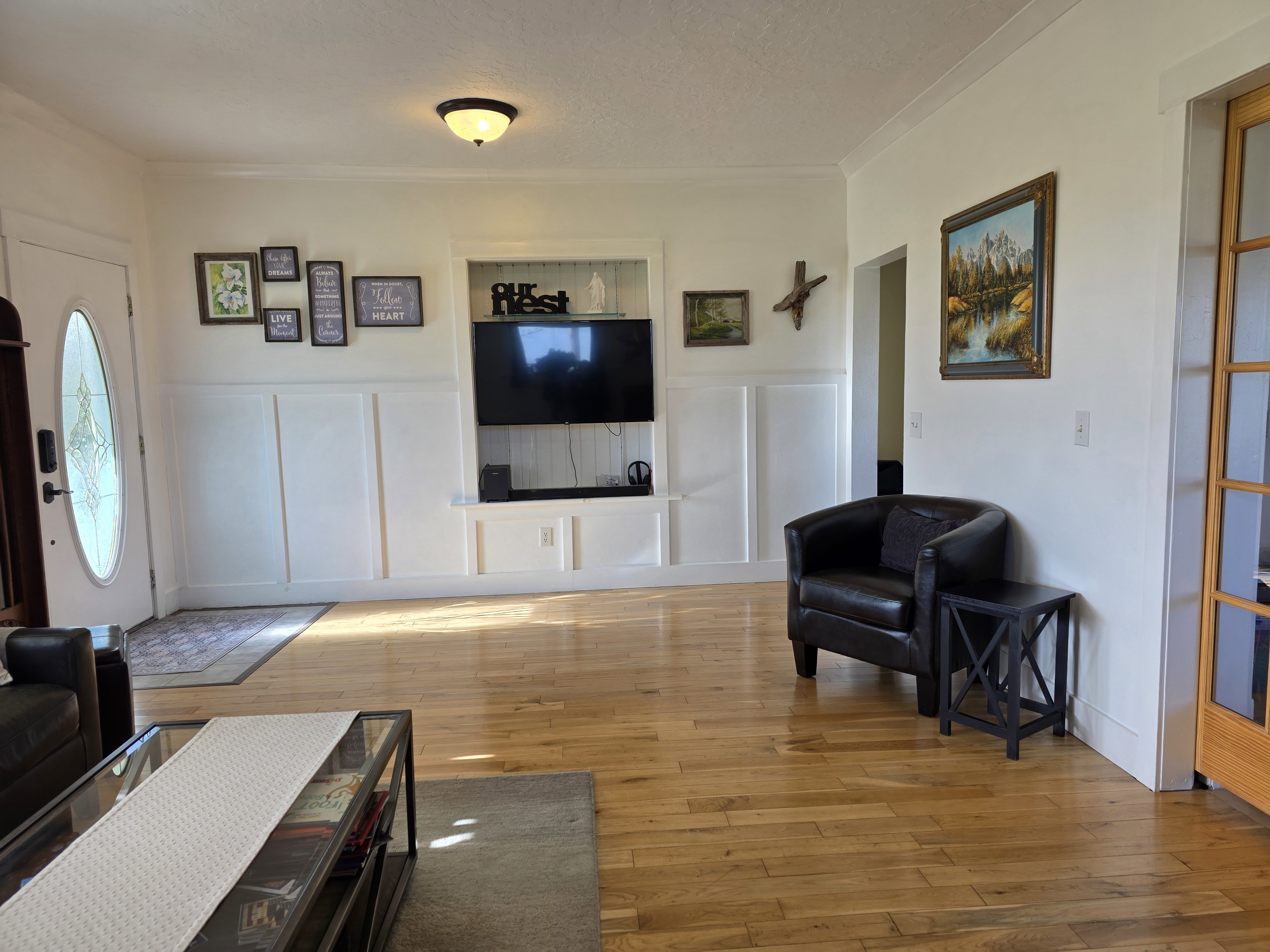Living area featuring a decorative wall, light wood finished floors, a wainscoted wall, and ornamental molding