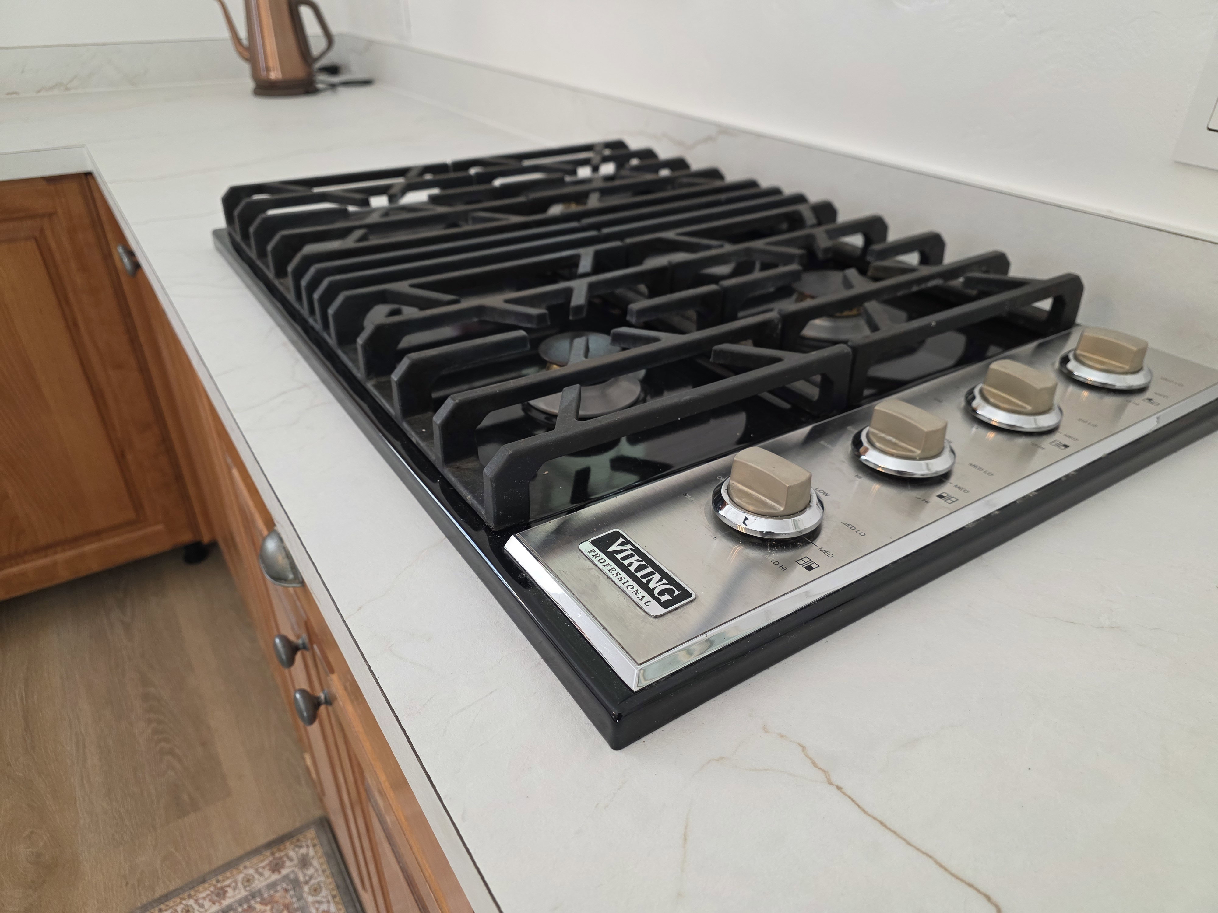 Kitchen view of stainless steel gas stovetop and wood finish cabinetry