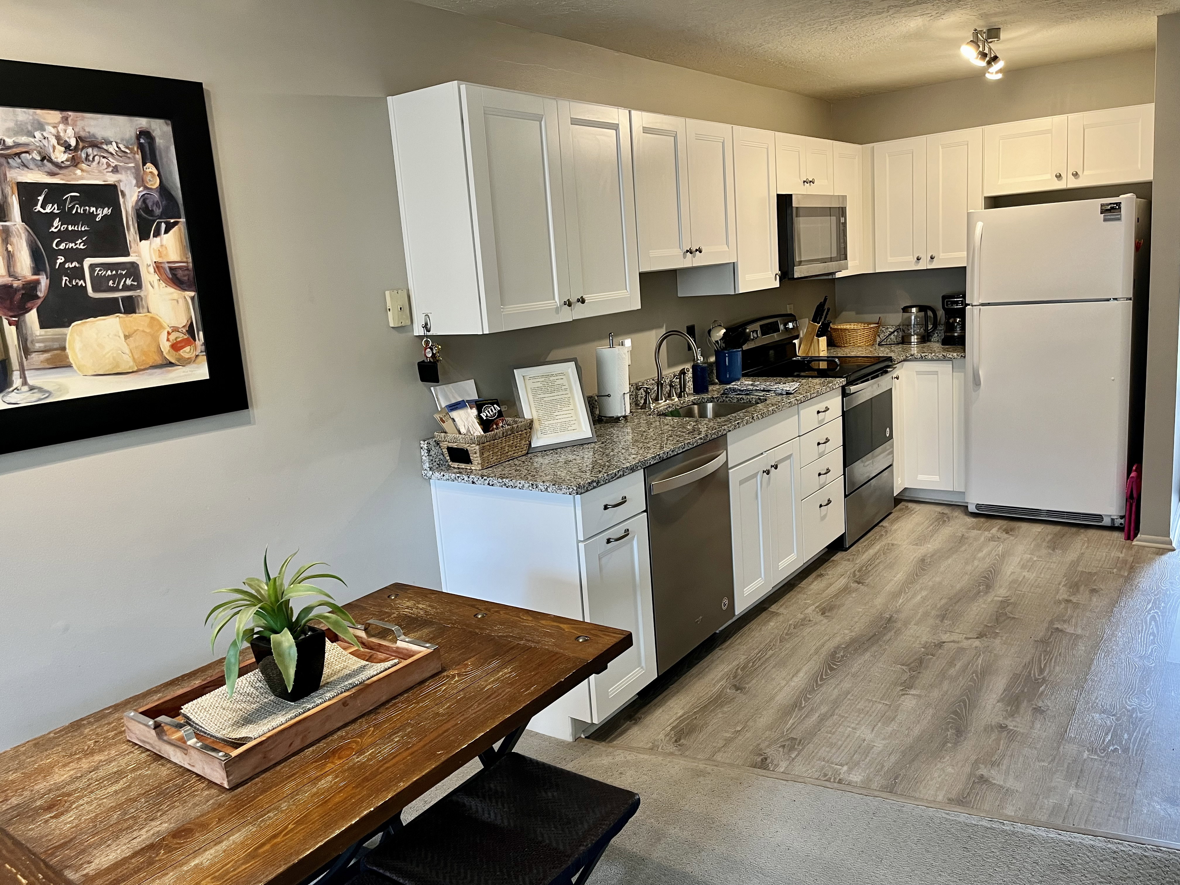 Remodeled Kitchen featuring stainless steel appliances, white cabinets, dark stone countertops, light wood-style flooring