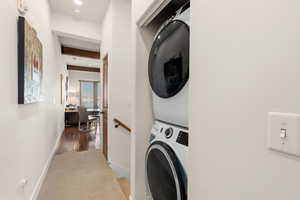 Laundry area with light carpet, stacked washer and dryer, recessed lighting, and beamed ceiling