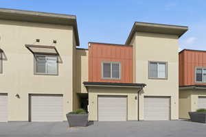 View of front of home featuring board and batten siding, a garage, stucco siding, and driveway