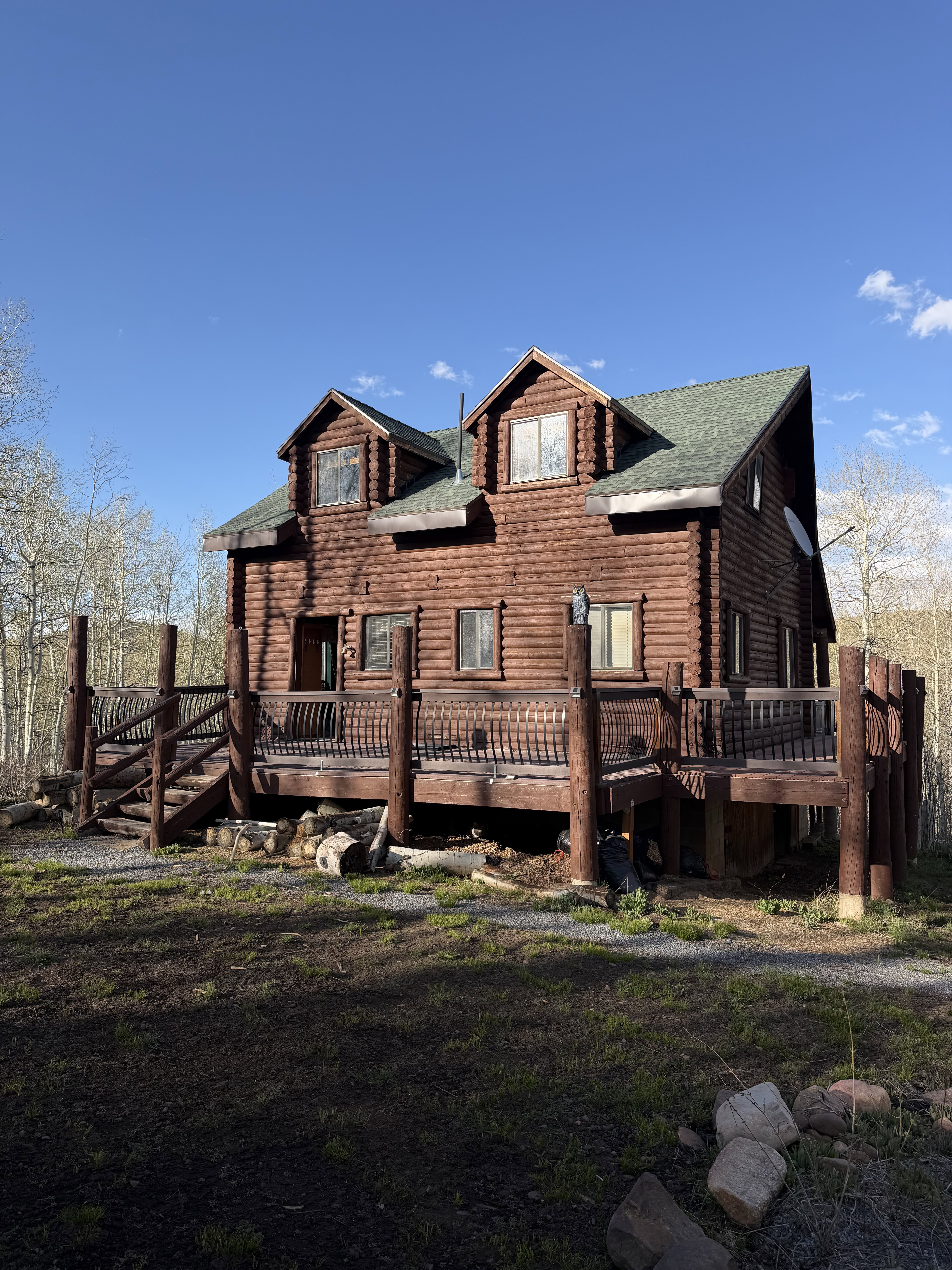 Back of property with a wooden deck, roof with shingles, and log exterior