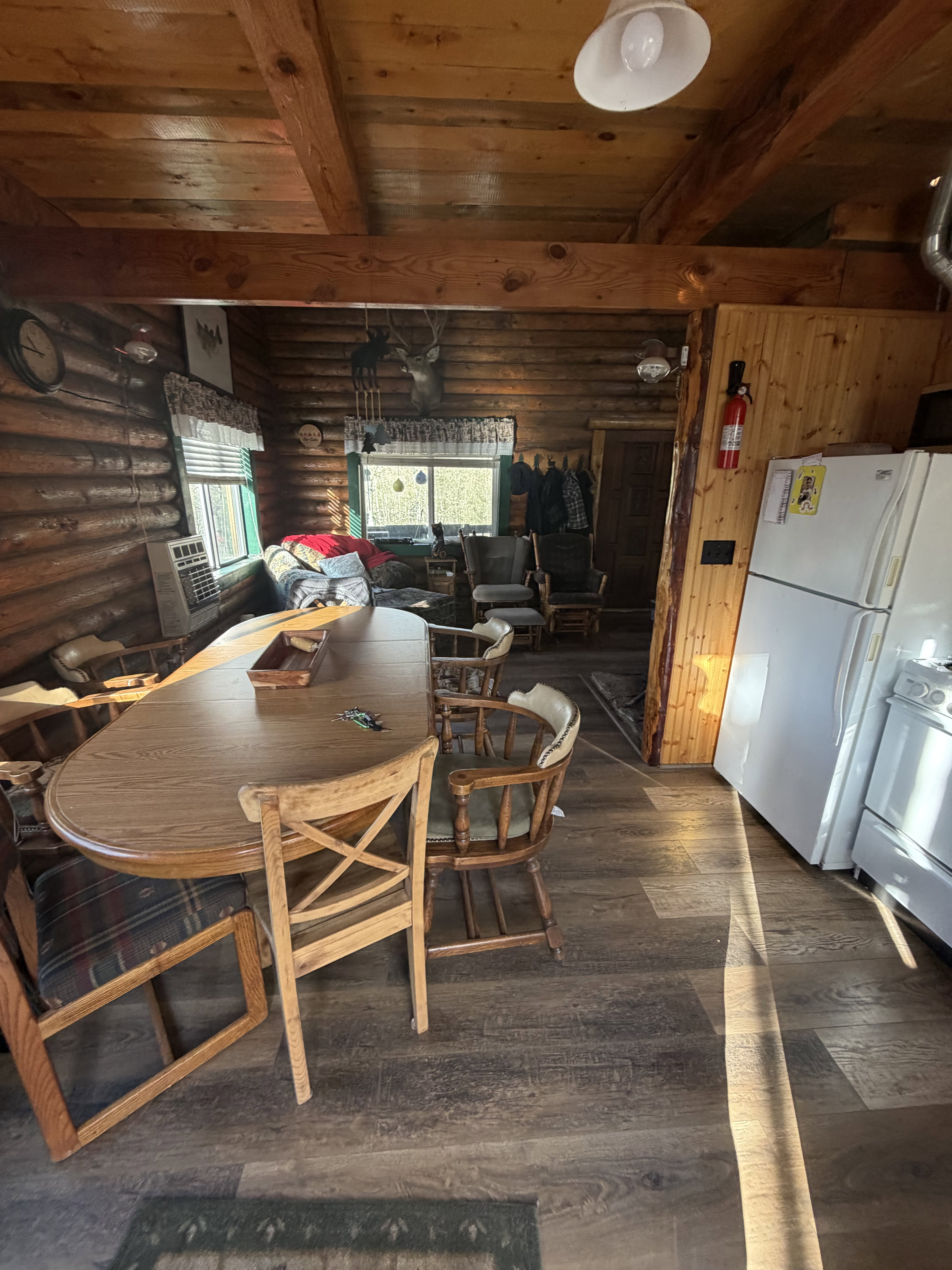 Dining area with a wooden ceiling with exposed beams, dark wood-style flooring, heating unit, and rustic walls
