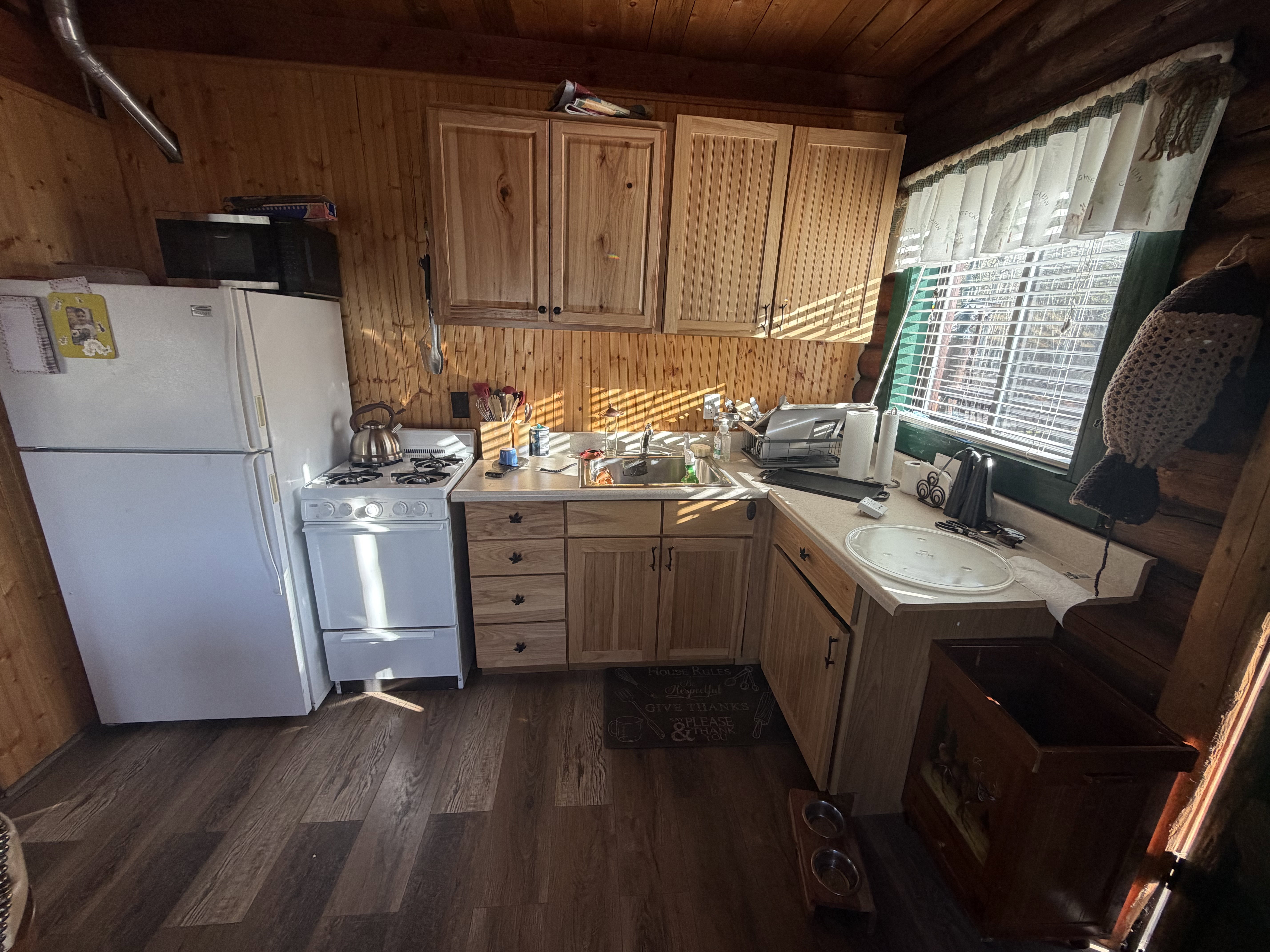 Kitchen with white appliances, light countertops, dark wood-style floors, wood walls, and wood finish cabinets