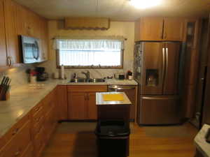 Kitchen with stainless steel appliances, light countertops, backsplash, and wood finish cabinets