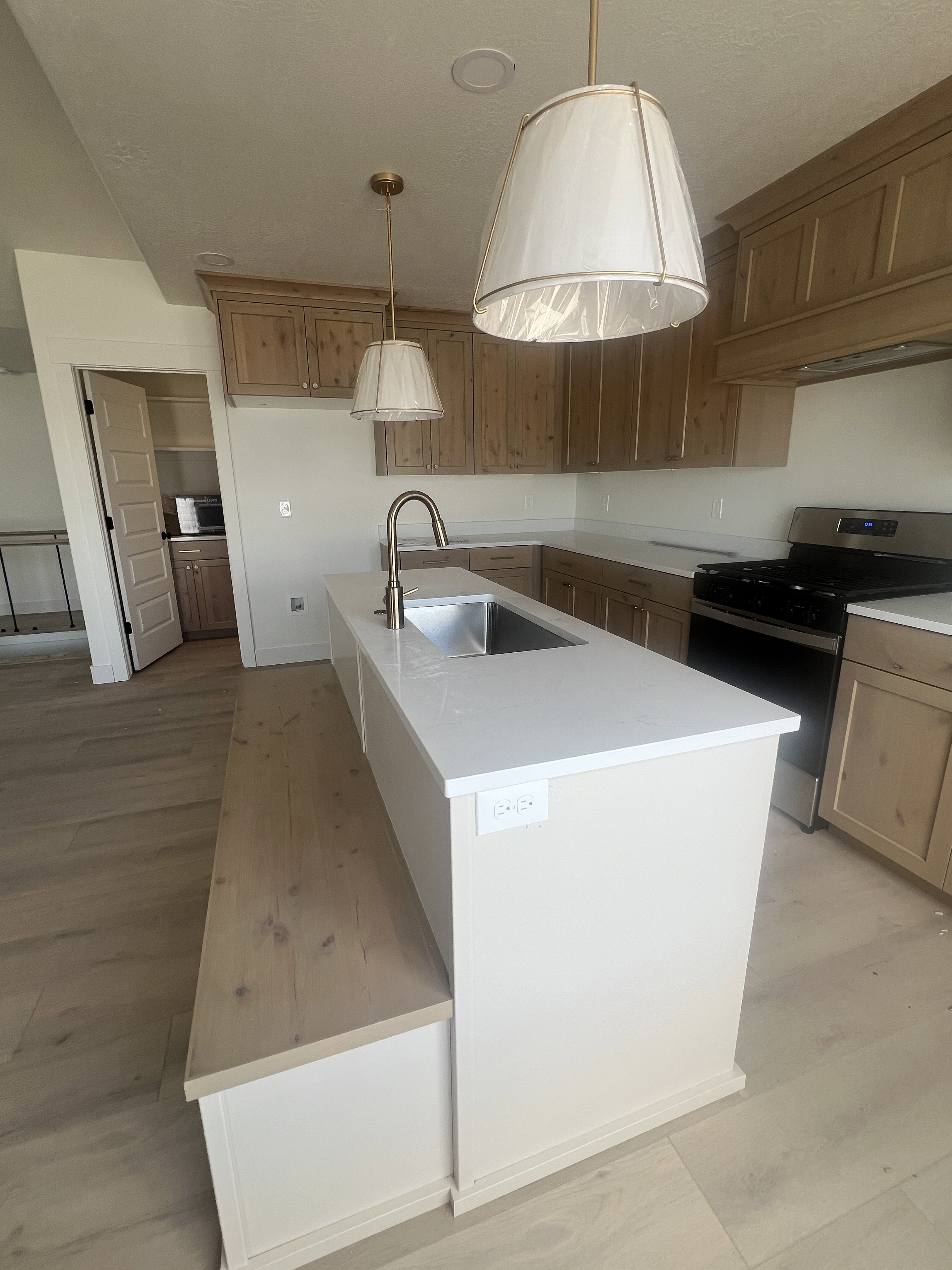 Kitchen featuring a central island with a built-in wood-finish bench, an undermount stainless steel sink, and quartz countertops