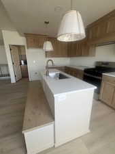 Kitchen featuring a central island with a built-in wood-finish bench, an undermount stainless steel sink, and quartz countertops