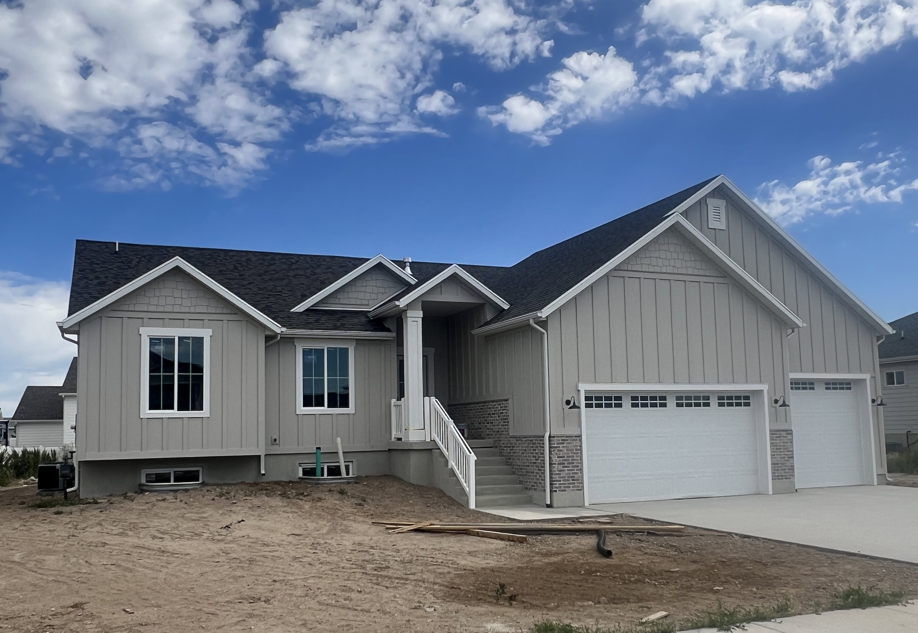 Contemporary single-story residence featuring a dark shingle roof and light gray vertical siding