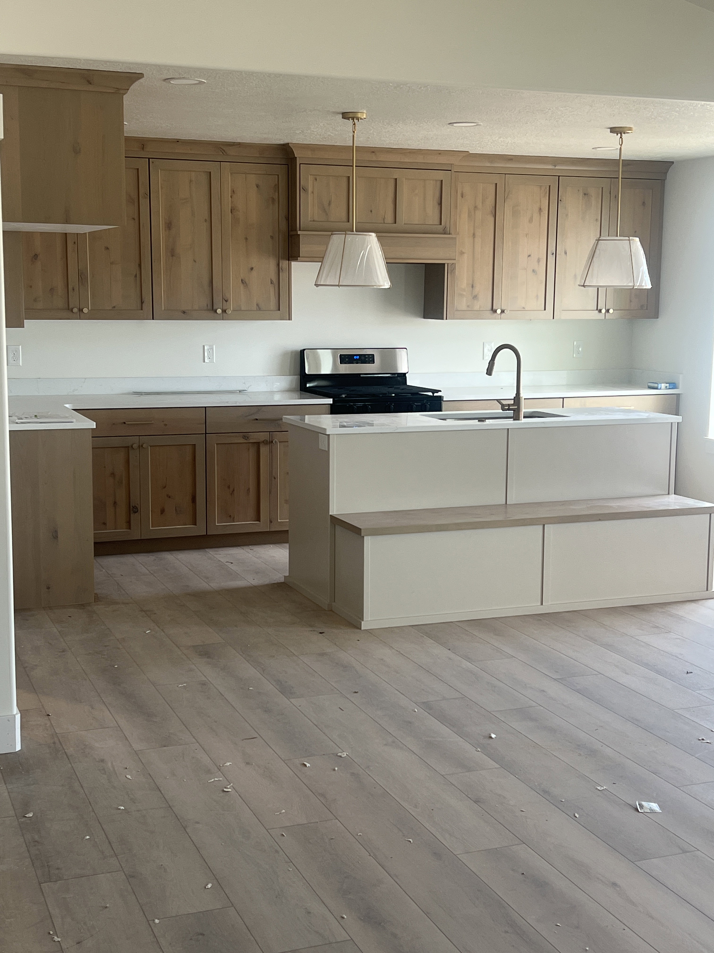 Spacious kitchen featuring wood-finish flooring, custom cabinetry, white countertops, built-in stainless steel appliances, and a central island with integrated seating