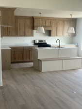 Spacious kitchen featuring wood-finish flooring, custom cabinetry, white countertops, built-in stainless steel appliances, and a central island with integrated seating