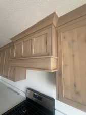 Custom wood cabinetry with crown molding, integrated range hood, and stainless steel gas range