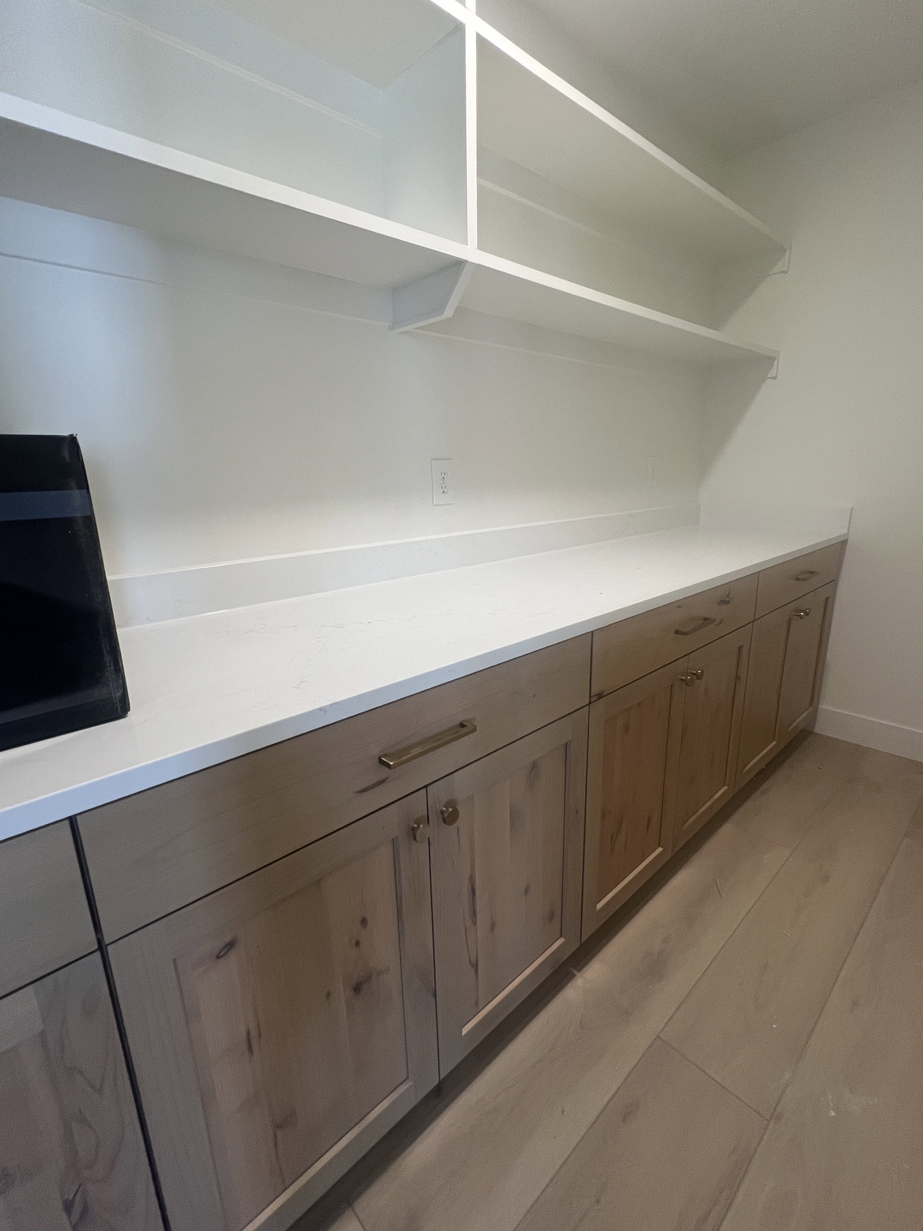 Custom built-in cabinetry with wood-finish doors, brushed brass hardware, and a light-toned countertop