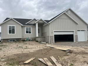 View of front facade with board and batten siding, roof with shingles, a garage, and dirt driveway