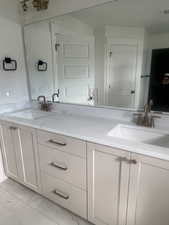 Dual vanity with light-colored cabinetry and stone-finish countertops
