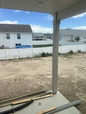 Covered patio space featuring a concrete slab and a white vinyl privacy fence