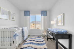 Bedroom with a crib, light colored carpet, and a mountain view