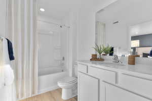 Bathroom with vanity, light wood-type flooring, shower / bathtub combination with curtain, and recessed lighting