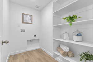 Laundry area featuring light wood-style floors, hookup for a washing machine, and electric dryer hookup