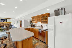 Kitchen with white fridge with ice dispenser, glass insert cabinets, recessed lighting, light countertops, and dishwasher