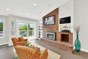 Living room featuring lofted ceiling, a brick fireplace, light wood-style flooring, recessed lighting, and built in features