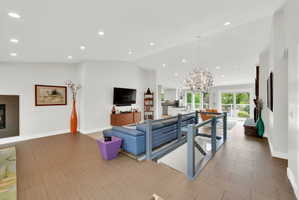 Living room with a glass covered fireplace, suspended lighting, vaulted ceiling, and french doors