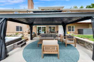 View of patio featuring a hot tub, an outdoor hangout area, and a gazebo
