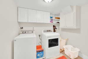 Laundry room featuring cabinet space, washing machine and dryer, and light tile patterned floors