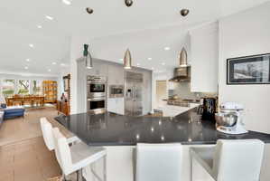 Kitchen featuring a breakfast bar area, a peninsula, built in appliances, tasteful backsplash, and open floor plan
