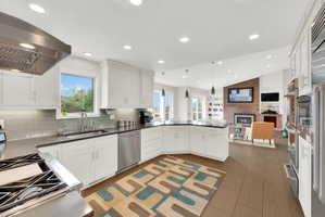 Kitchen featuring a fireplace, decorative light fixtures, white cabinets, stainless steel appliances, and vaulted ceiling