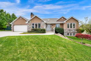 View of front of property featuring stone siding, an attached garage, driveway, and stucco siding