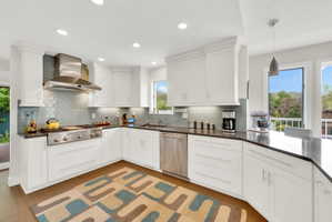 Kitchen with white cabinetry, stainless steel appliances, hanging light fixtures, and decorative backsplash
