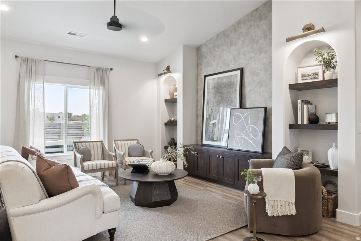 Living room with light wood finished floors, built in features, and recessed lighting