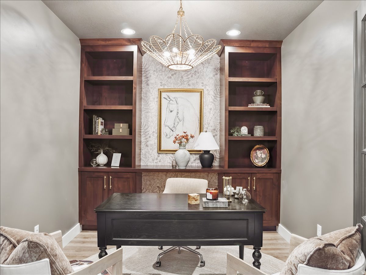 Office area with built in shelves, a chandelier, and light wood-style floors