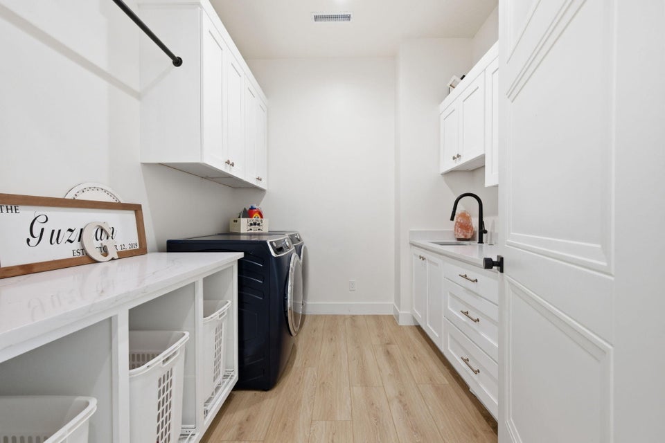 Laundry room with light wood finished floors, washer and clothes dryer, and cabinet space